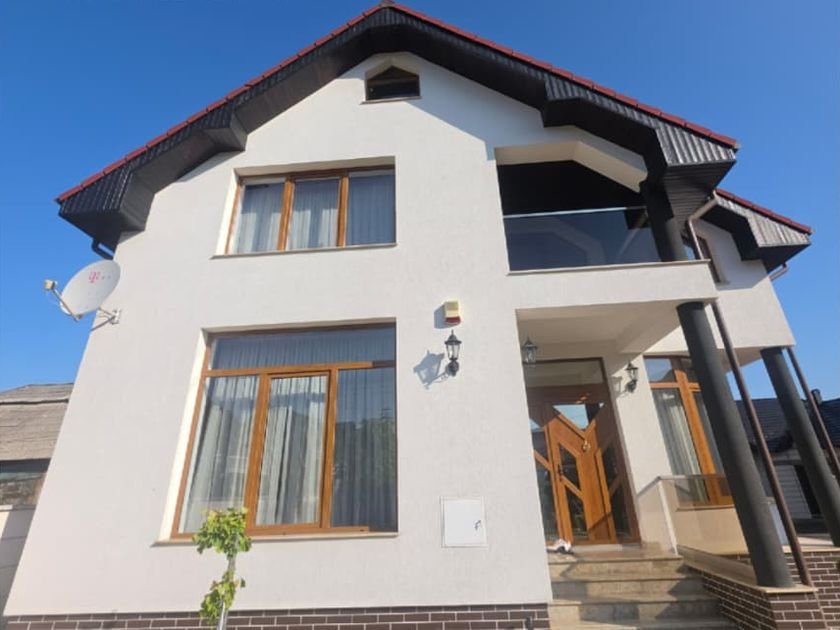 Aceeași casă după spălare, cu fațada albă curată și soclul de cărămidă